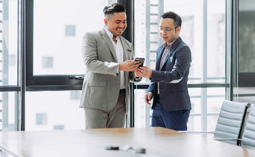 two men looking at a phone in an office